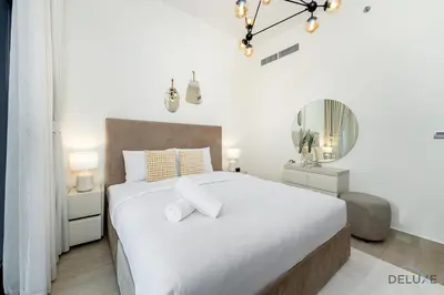 a white bedroom with a large bed and a mirror at Comfy 1BR in Azizi Riviera 8, Al Merkadh by Deluxe Holiday Homes in Dubai