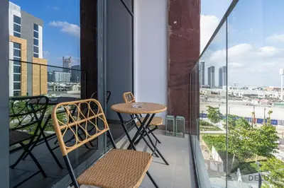 a balcony with a table and chairs and a view at Comfy 1BR in Azizi Riviera 8, Al Merkadh by Deluxe Holiday Homes in Dubai