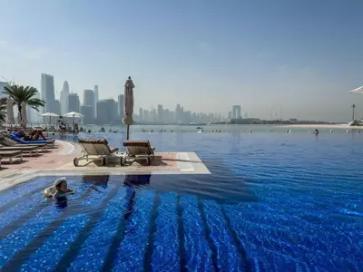 a person swimming in a swimming pool with a city in the background at Exquisite 1BR Hidden Gem - Oceana Residences in Dubai