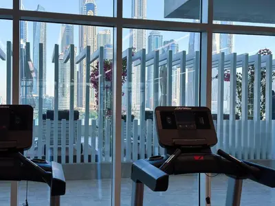 a gym with a view of the city through the window at Vibrant 1BR Apartment with Marina & Ocean View in Dubai