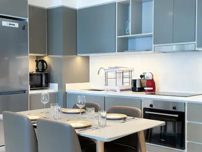 a kitchen with blue cabinets and a table with wine glasses at Vibrant 1BR Apartment with Marina & Ocean View in Dubai