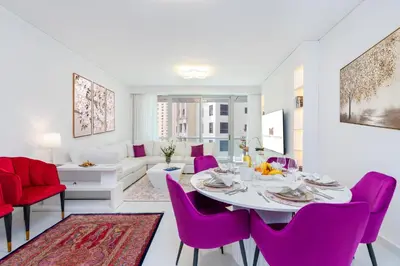 a living room with a table and purple chairs at High class apartment in Dubai