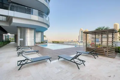a patio with lounge chairs and a pool on a building at RH- Elevated Living, Modern 1BR Oasis at RP Heights walk away to Dubai Mall in Dubai