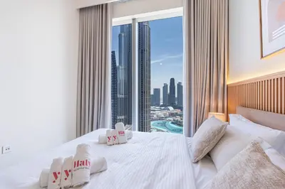 a bedroom with a white bed with a view of a city at Luxury 3BHK, Burj Khalifa & Dancing fountain view in Dubai