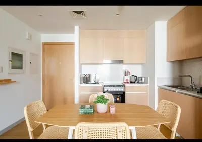 a kitchen with a wooden table and chairs in a kitchen at Exquisite 1-Bedroom with Pool Scenery in Dubai Creek Harbour in Dubai