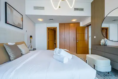 a bedroom with a large white bed and a chair at Luxury 3BR in Ocean Heights, Dubai Marina by Deluxe Holiday Homes in Dubai