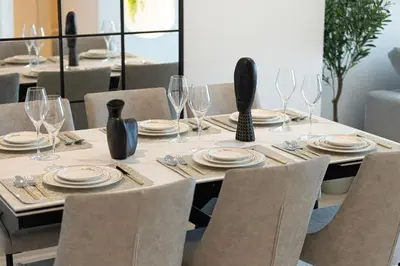 a table with chairs and plates and wine glasses at Burj Khalifa View & Dubai Mall Connection in Dubai