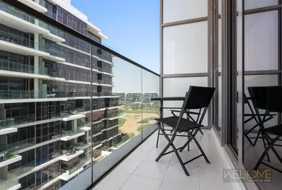 a balcony with two chairs and large windows at WelHome - Charming Breathtaking 1BR Apt. In Damac Hills in Dubai