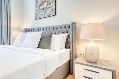 a bedroom with a bed with a lamp on a nightstand at RH - Spacious chic apartment, Next to Dubai Mall in Dubai
