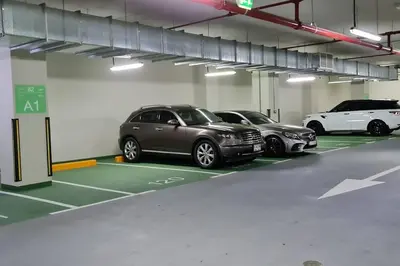a parking garage with three cars parked in it at quiet green 1 bedroom for your rest in Dubai