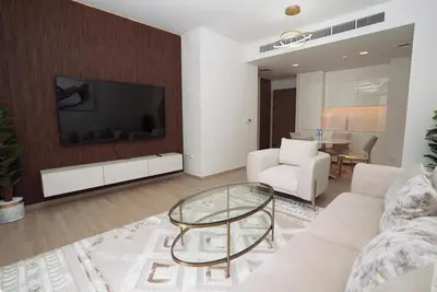 a living room with a couch and a tv on a wall at High Floor, 1 Bedroom in Palace Residence in Dubai