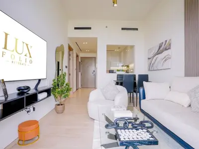 a living room with a white couch and a table at Stylish JVC 1 Bedroom Sanctuary in Dubai
