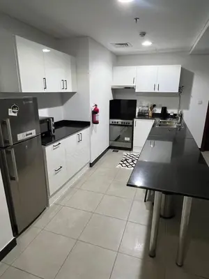 a kitchen with white cabinets and a black counter top at Specious cosy bedroom in Al Sufouh in Dubai