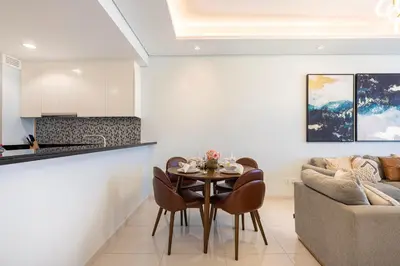 a kitchen and living room with a table and a couch at 2BR High Floor Infinity Pool w/ Burj Khalifa view in Dubai