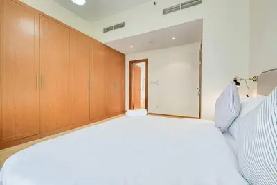 a large white bed in a room with wooden cabinets at Exclusive 2BR Apartment in Madison Residency - Close to Dubai Internet City Metro Station in Dubai