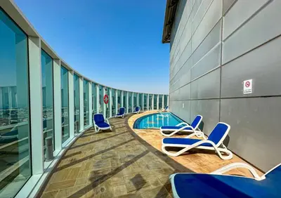 a balcony with chairs and a swimming pool on a building at Exclusive 2BR Apartment in Madison Residency - Close to Dubai Internet City Metro Station in Dubai