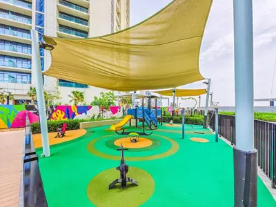 a playground with a slide and swings at Modern and Cozy Condo With Unobstructed City Views in Dubai