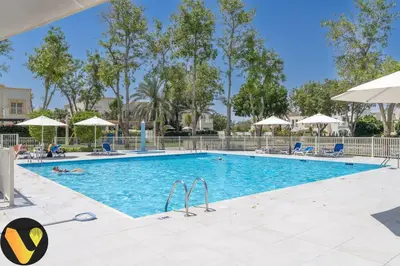 a pool at a resort with people swimming in it at Vogue Springs Emirates Living near The Springs Souk, JBR, Marina, Mall of the Emirates, Spacious Villa with Garden and access to Lake and all Amenities in the Community in Dubai