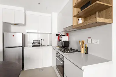 a white kitchen with white cabinets and a refrigerator at Silkhaus High Floor Luxury 1BDR in New Tower in Dubai