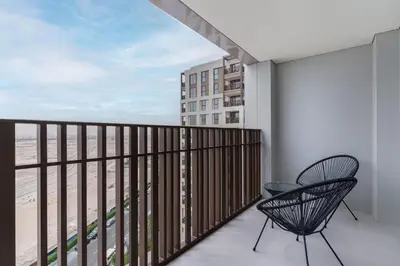 a balcony with two chairs and a view of a city at Spacious 1-Bedroom in Summer, Lagoon Access Feature - Allsopp&Allsopp in Dubai