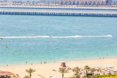 a beach with a group of people swimming in the water at Sound of the Waves in JBR by Lagom in Dubai
