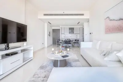 a white living room with a white couch and a table at Elegant 1BR Apartment with Free Beach Access in Dubai