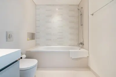 a white bathroom with a tub and a toilet at Elegant 1BR Apartment with Free Beach Access in Dubai