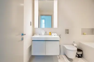 a bathroom with a sink and a toilet and a mirror at Elegant 1BR Apartment with Free Beach Access in Dubai