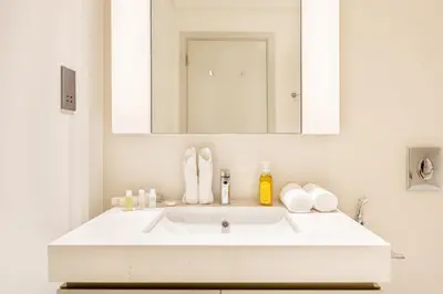 a white bathroom with a sink and a mirror at Elegant 1BR Apartment with Free Beach Access in Dubai