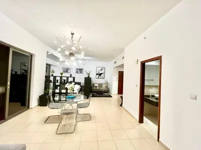 a living room with a glass table and a chandelier at Spacious Full Sea View Full Apartment in Dubai