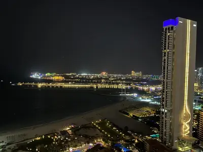 a view of a city at night with a tall building at Spacious Full Sea View Full Apartment in Dubai