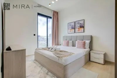 a bedroom with a large bed with pink pillows at Mira Holiday Homes - Lovely serviced apartment with pool access in Dubai