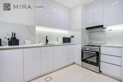 a white kitchen with a stove and a microwave at Mira Holiday Homes - Lovely serviced apartment with pool access in Dubai