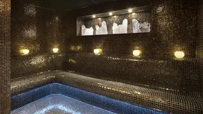 a black tiled bathroom with a swimming tub with lights at DAMAC Maison Cour Jardin in Dubai