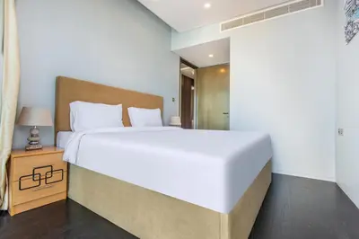 a bedroom with a large white bed and a night stand at Damac Heights by Fendi in Dubai