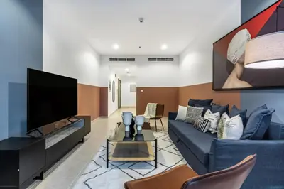 a living room with a blue couch and a flat screen tv at The Smart Concierge - Elite residence in Dubai