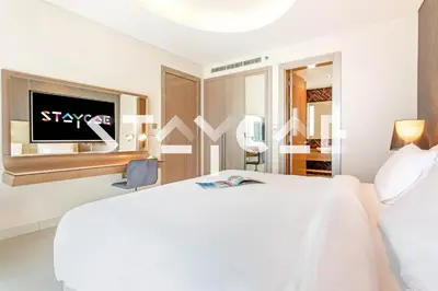a white bedroom with a bed and a tv at Staycae Holiday Homes - Damac Towers By Paramount in Dubai