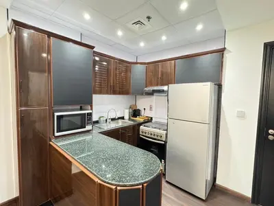 a kitchen with a white refrigerator and a counter top at Stay in the heart of Sport City in LUX 1BDR with sky view 11 in Dubai