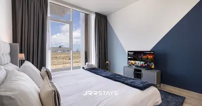 a bedroom with a bed with a tv and a window at Sophisticated Studio JVC - Breathtaking City View in Dubai