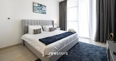 a bedroom with a large bed with a blue rug at Sophisticated Studio JVC - Breathtaking City View in Dubai