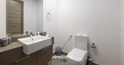 a bathroom with a white toilet and a sink at Sophisticated Studio JVC - Breathtaking City View in Dubai