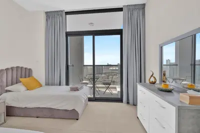 a bedroom with a bed and a large window at Stylish 2BR for 6 with King Beds, Pool, Gym in JVC in Dubai