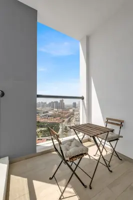 a table and chair on a balcony with a view at Stylish 2BR for 6 with King Beds, Pool, Gym in JVC in Dubai