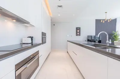 a kitchen with white counters and a sink at Serene and sophisticated Lagoon Living - Suiteable in Dubai