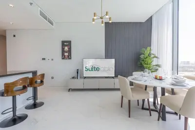 a living room with a dining table and a tv at Serene and sophisticated Lagoon Living - Suiteable in Dubai