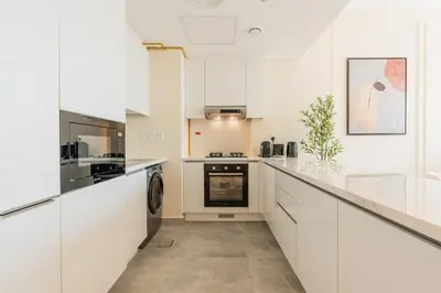 a white kitchen with white cabinets and appliances at Every Sunset is a Masterpiece in Catch Residence in Dubai