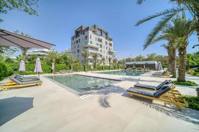 a swimming pool with lounge chairs and a building at Stella Stays Al-Barari in Dubai