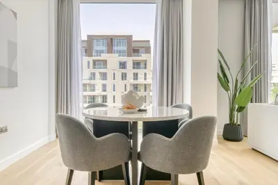 a dining room with a table and chairs and a window at Stella Stays Al-Barari in Dubai