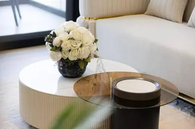 a glass table with a vase of flowers on it at Fully Furnished Luxe 1BR In JVC in Dubai