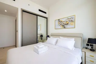 a bedroom with a large white bed with white pillows at Fully Furnished Luxe 1BR In JVC in Dubai
